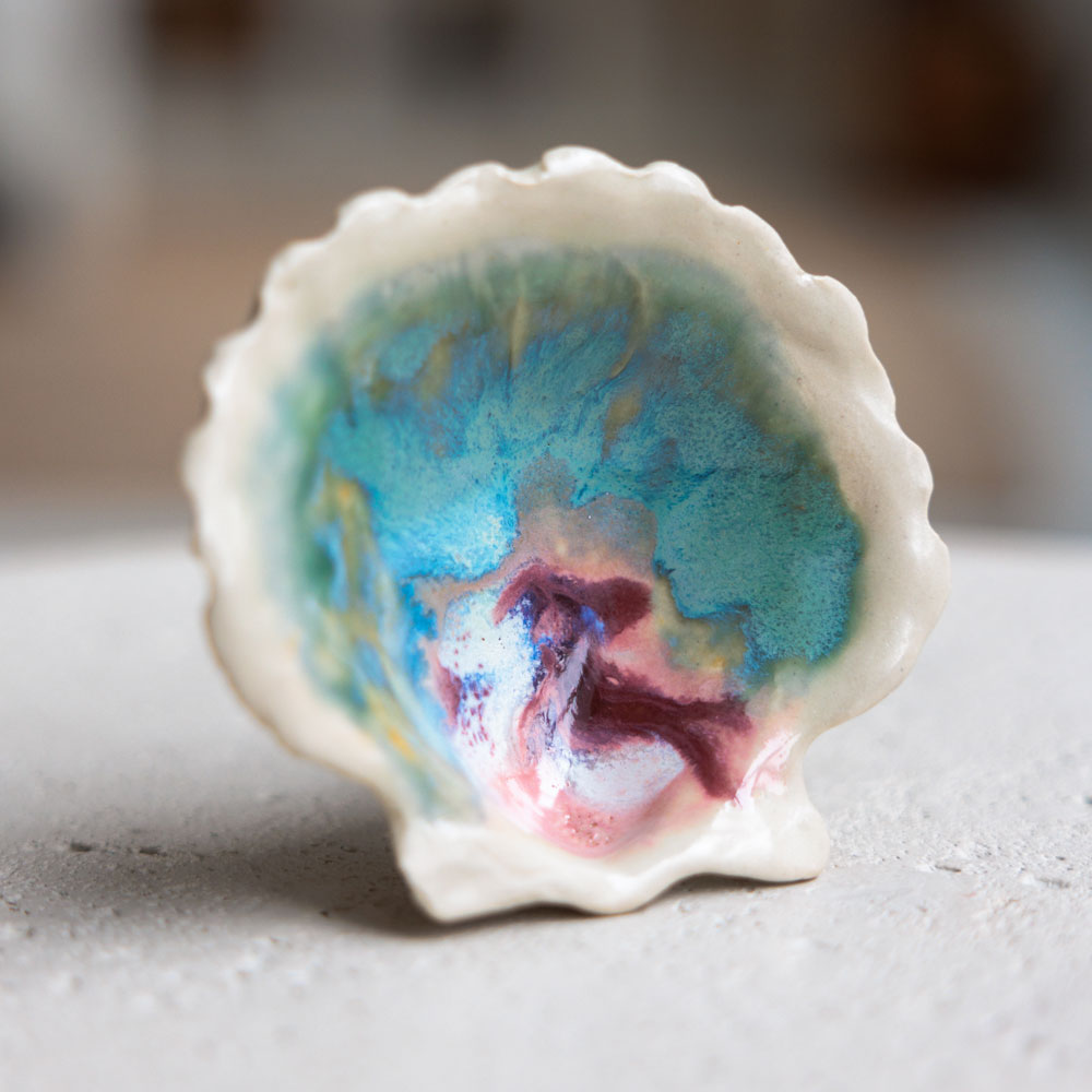 A ceramic seashell with a turquoise and pink interior