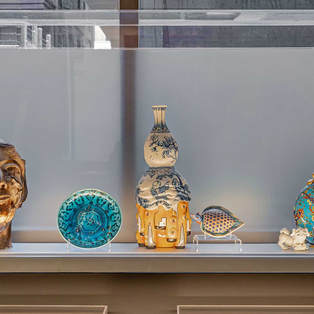 A grouping of diverse ceramic objects in a glass vitrine