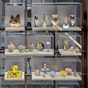 An assortment of ceramic objects displayed in a series of glass vitrines in a window