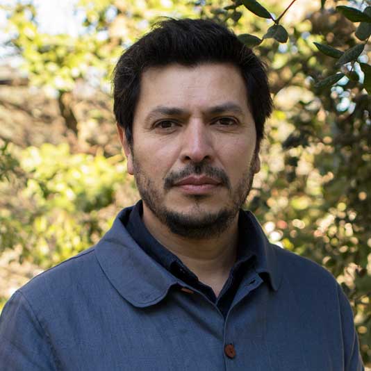 Francisco Huichaqueo wearing a blue jacket with trees behind him