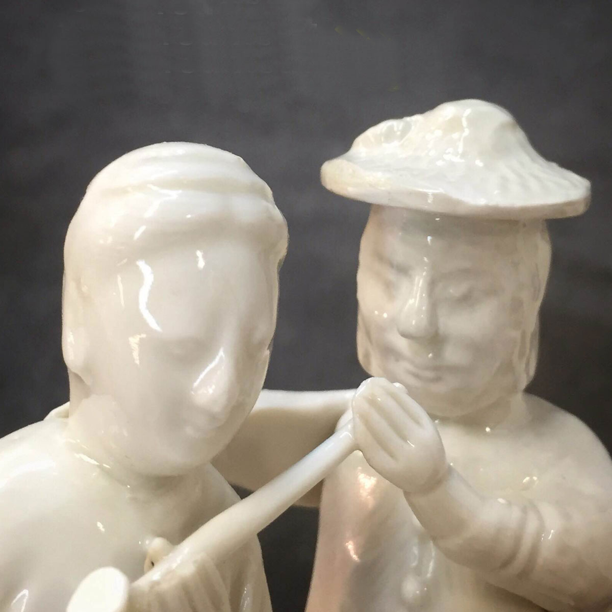 Two white ceramic figures, one with a pipe