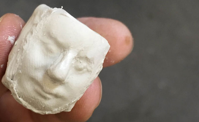 Hand holding white clay head