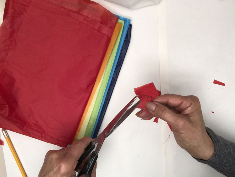 Cutting a leaf out of red tissue paper