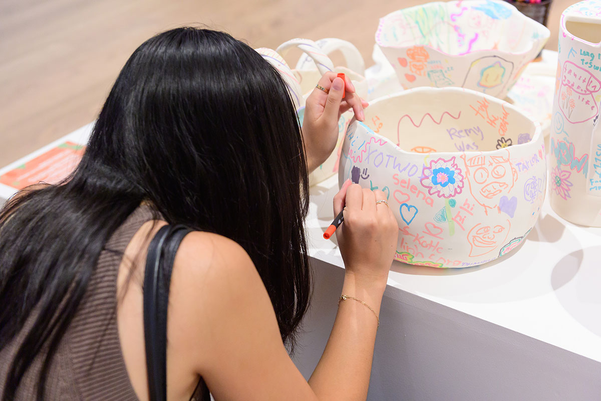 A woman drawing on a white ceramic vessel