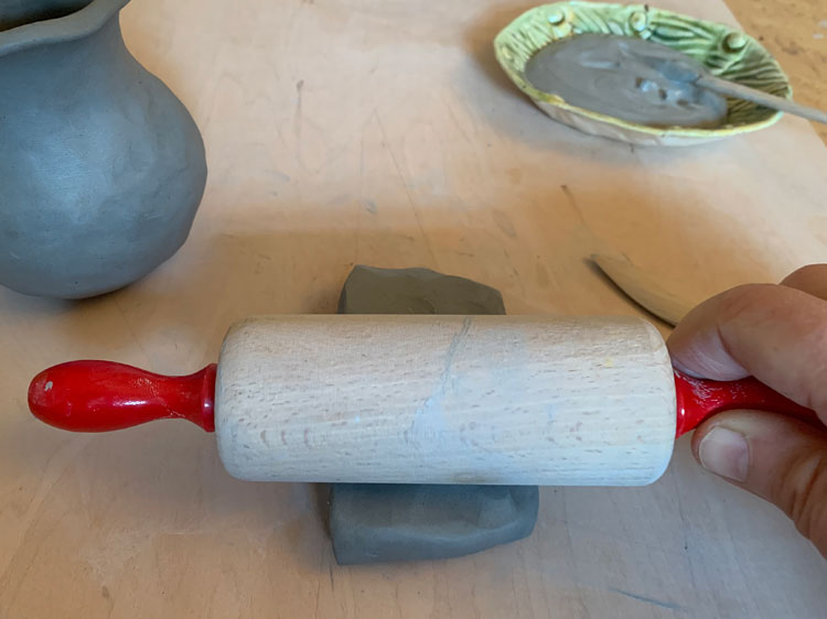 Rolling out a piece of clay with a rolling pin