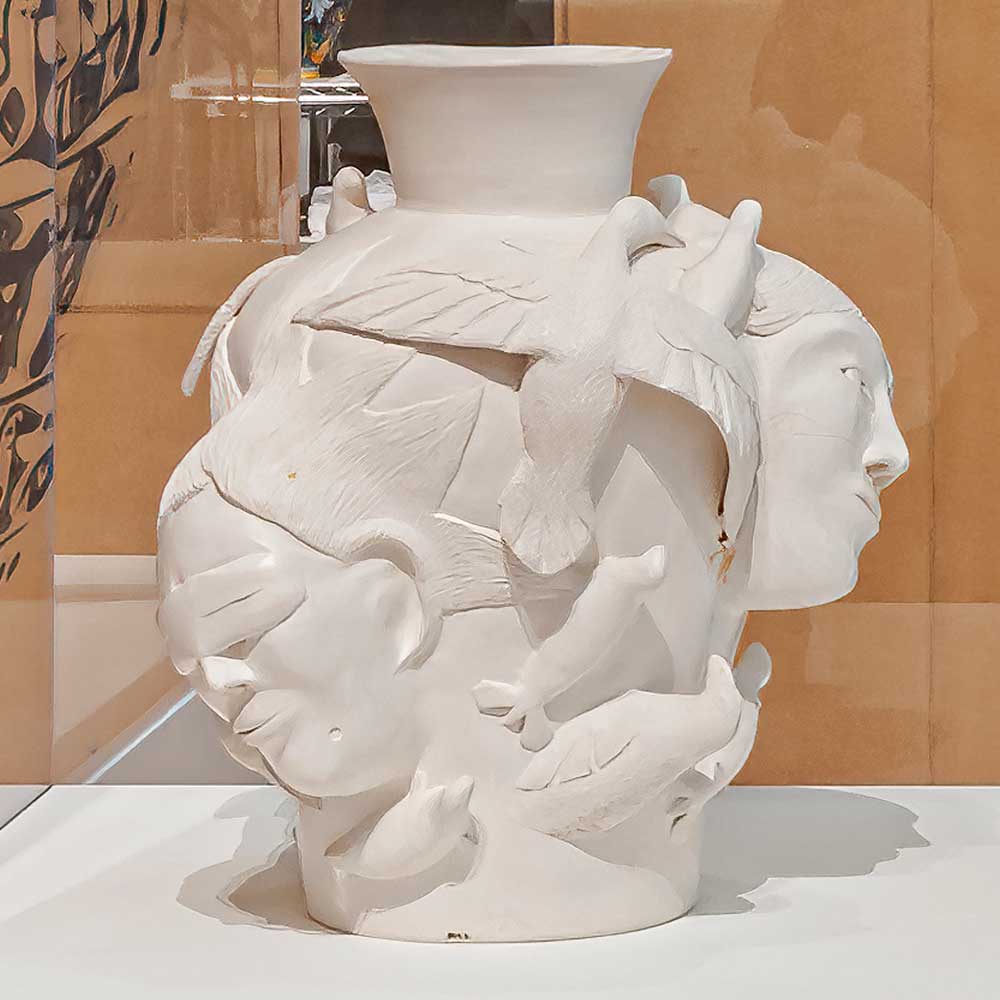 A white ceramic vase with sculptures of Inuit people and arctic animals