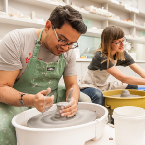 A man and woman using the pottery wheel