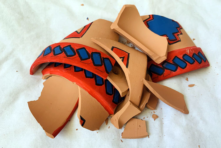 Shards of a clay pot with red and blue painted designs