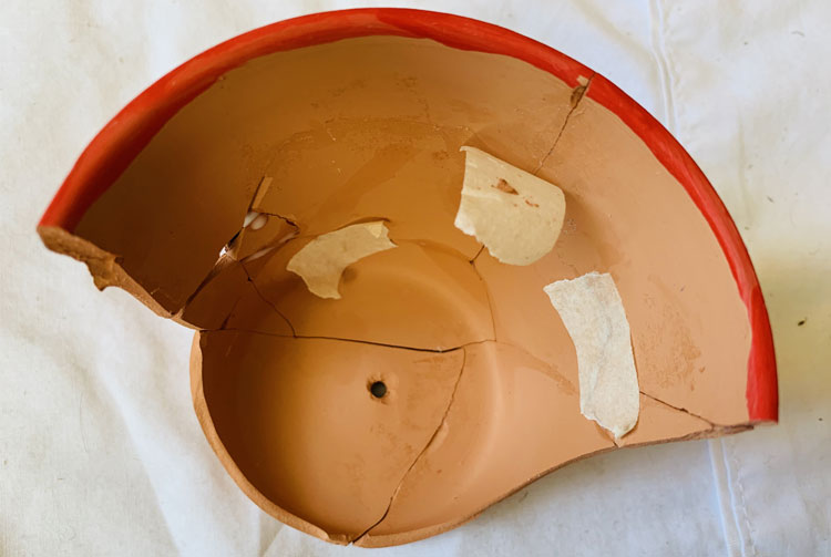 Broken clay pot with cracks held together with tape