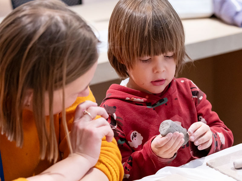 A mother watching her child play with a lump of clay