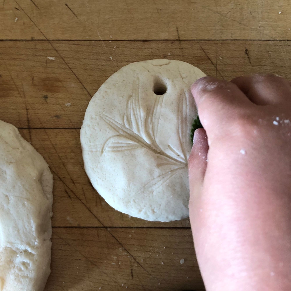 Hand pressing leaves into dough