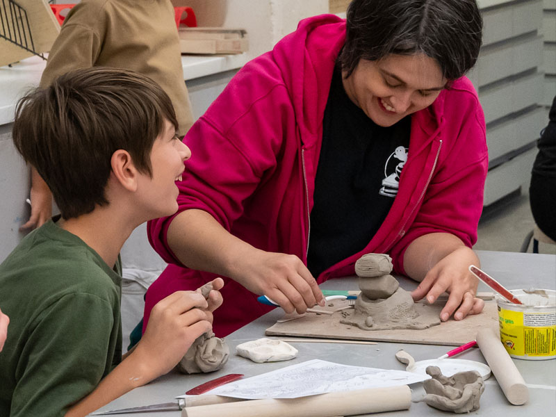 A mother and son laughing while making pottery in the studio