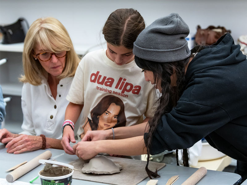 An adult and child getting pottery instruction