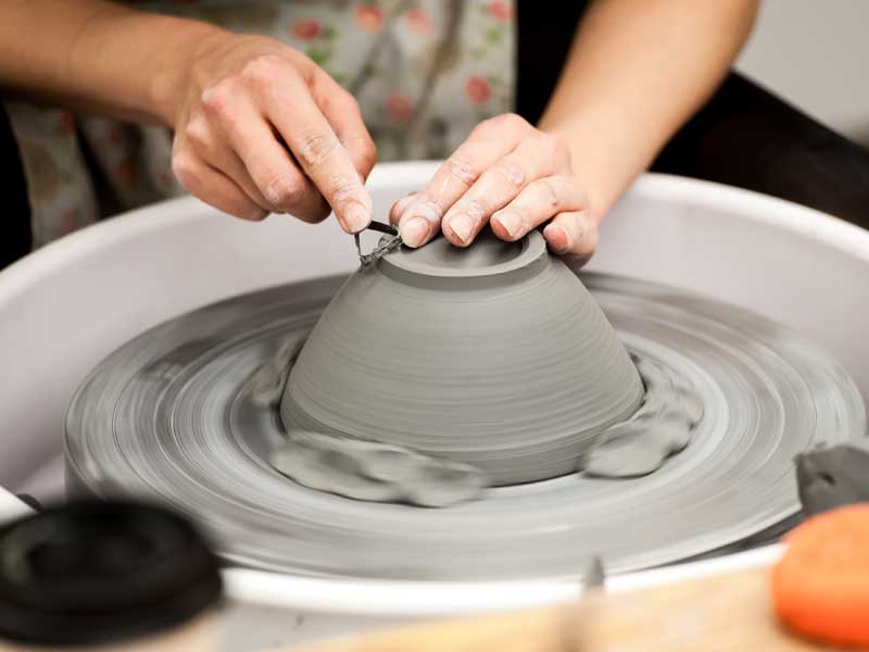 Hands of someone making a vessel on the pottery wheel